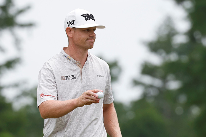 Patrick Fishburn grins while holding a golf ball